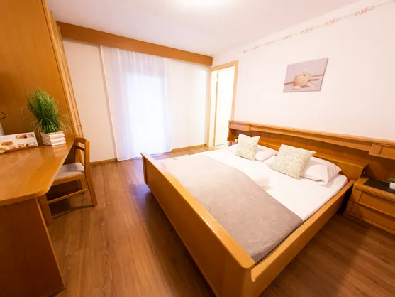 Gemütliches Doppelzimmer mit hellem Holzbett, Schreibtisch, TV und Laminatboden