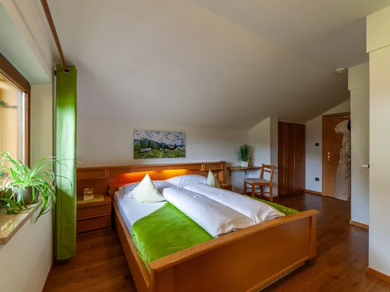 Gemütliches Dachgeschoss-Zimmer mit Holzbett, Bademantel und alpinem Alm-Motiv